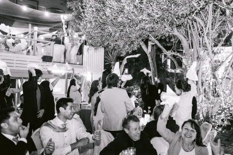 Grupo de personas levanta los brazos mientras vuelan papeles, en una fotografía en blanco y negro.