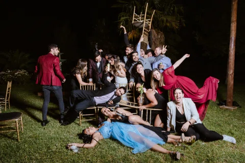 Grupo de personas posa en el césped durante la celebración nocturna, con algunas sentadas y otras de pie.