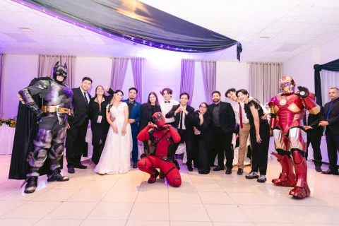 Grupo de personas posa dentro del salón junto a varias figuras con disfraces de colores.