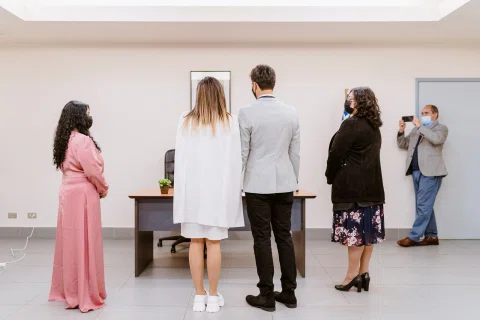 Varias personas reunidas de pie frente a una mesa dentro de la oficina.