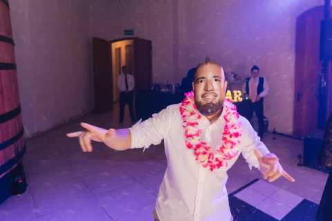 Hombre con camisa blanca y collar de flores baila solo frente a la cámara.