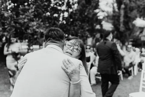Hombre con chaqueta clara abraza a una mujer con camisa clara, en una fotografía en blanco y negro.