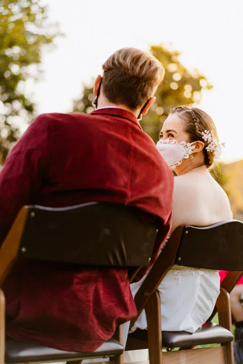 Hombre con chaqueta roja y mujer con vestido blanco sentados lado a lado.
