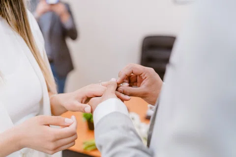 Primer plano de un hombre colocando un anillo en la mano de una mujer.
