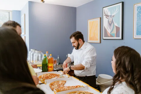 Hombre cortando una pizza sobre una mesa durante la celebración.