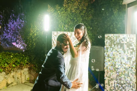 Hombre con traje azul y mujer con vestido blanco bailan juntos bajo una luz verde.