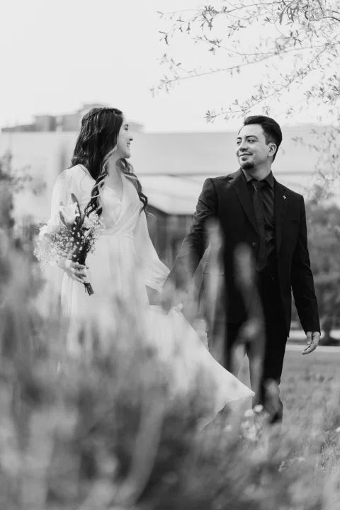 Hombre y mujer caminan entre flores en una fotografía en blanco y negro.