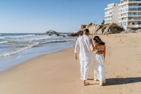 Hombre y mujer caminan de espaldas por la orilla del mar.