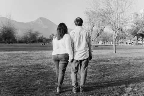 Hombre y mujer caminan de espaldas por un parque en una fotografía en blanco y negro.