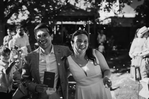 Hombre y mujer caminan sonriendo frente al gazebo en una fotografía en blanco y negro.