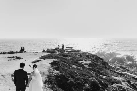 Hombre y mujer aparecen de espaldas frente a un paisaje costero, en blanco y negro.
