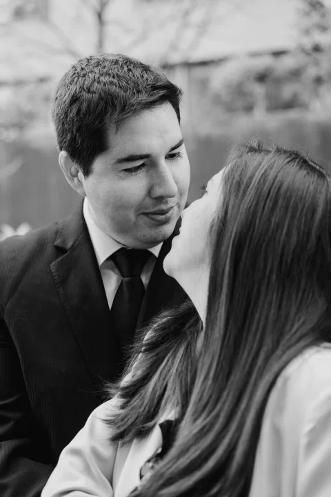 Hombre con traje oscuro y mujer de chaqueta clara se miran de cerca en una fotografía en blanco y negro.