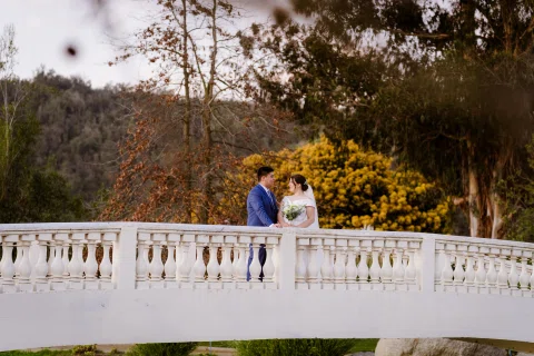Hombre y mujer permanecen juntos junto a la baranda de un puente blanco.
