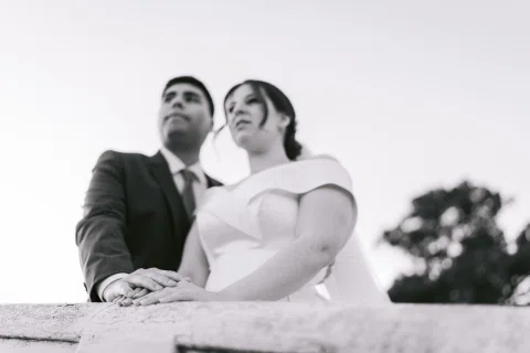 Hombre y mujer posan juntos desde un ángulo bajo con cielo claro al fondo.