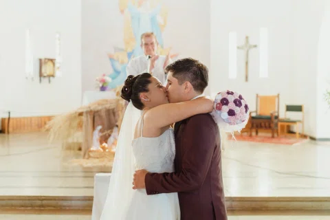 Hombre y mujer se besan abrazados frente al altar de una iglesia.