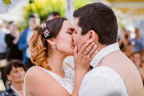 Hombre y mujer se besan en un primer plano; las manos de la mujer están apoyadas en el rostro del hombre.