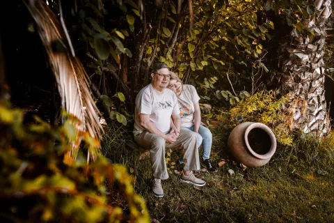 Hombre y mujer sentados juntos bajo un árbol en un jardín.