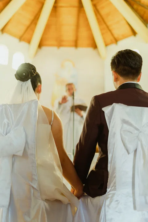 Hombre y mujer están sentados de espaldas frente al altar de una iglesia.