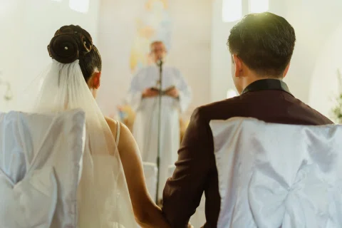 Hombre y mujer están sentados de espaldas mientras permanecen tomados de la mano frente al altar.