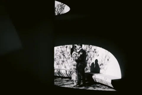 Silueta de un hombre y una mujer enmarcada por una abertura curva, en una fotografía en blanco y negro.
