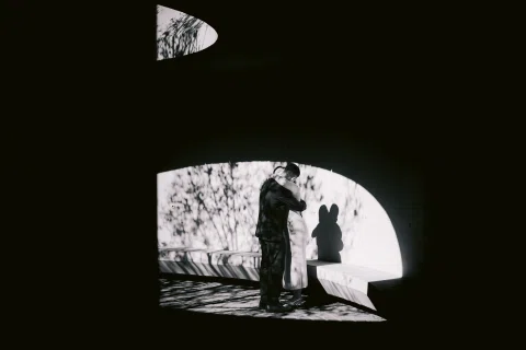 Silueta de un hombre y una mujer dentro de una estructura curva, en una fotografía en blanco y negro.