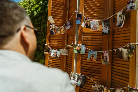 Hombre observa una serie de fotografías colgadas sobre paneles de madera al aire libre.