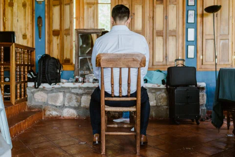 Hombre sentado de espaldas en una habitación de madera durante los preparativos.