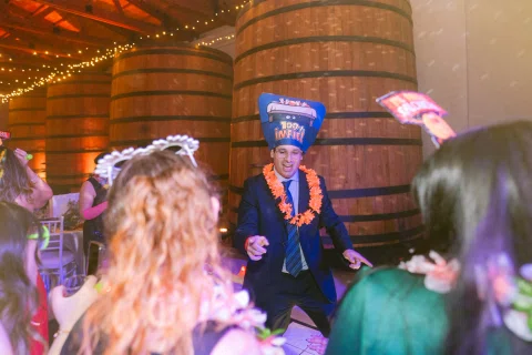 Hombre con traje azul y accesorio de fiesta baila entre varias personas dentro del salón.
