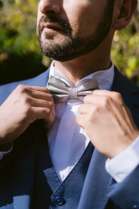 Primer plano de un hombre con traje azul ajustando su corbata.