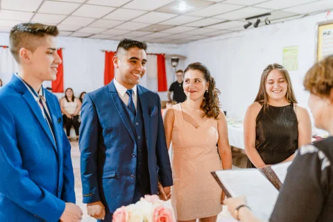Hombre con traje azul gesticulando mientras varias personas lo observan.