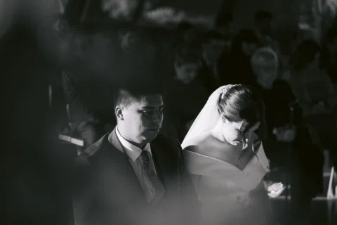 Hombre con traje azul y mujer con vestido blanco aparecen juntos en un retrato cercano en blanco y negro.