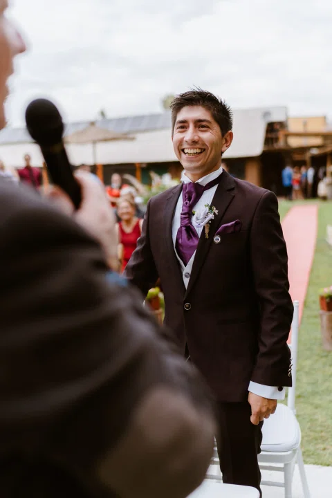 Hombre con traje oscuro permanece de pie y sonríe durante la ceremonia.