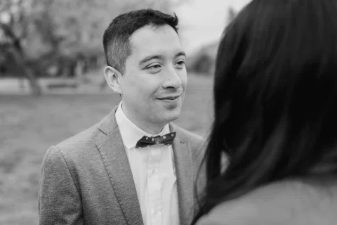 Hombre con traje gris mira hacia una mujer vista de espaldas, en blanco y negro.