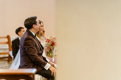 Hombre con traje oscuro sentado de perfil dentro de una iglesia.