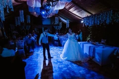 Hombre y mujer bailan en el salón bajo iluminación azul.