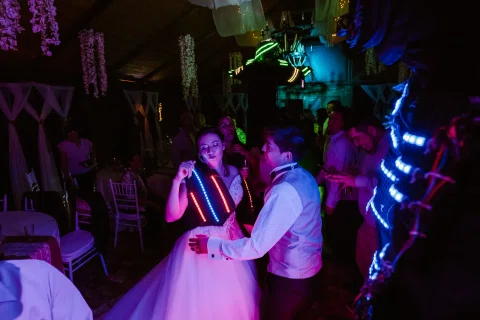 Hombre y mujer bailan en la pista junto a una persona con traje iluminado.