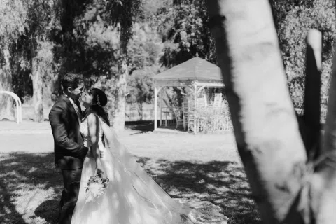 Hombre y mujer permanecen frente a frente en un jardín, fotografiados en blanco y negro.