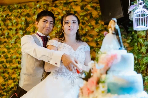 Hombre y mujer posan juntos detrás de una torta decorada con flores.
