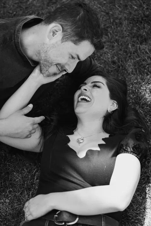 Hombre y mujer están recostados sobre el césped y se miran en una fotografía en blanco y negro.