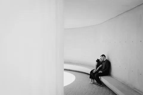 Hombre y mujer están sentados sobre una curva de hormigón en una fotografía en blanco y negro.