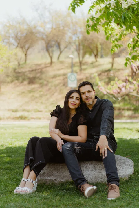 Hombre y mujer están sentados juntos sobre una piedra bajo árboles.