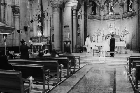 Vista en blanco y negro del interior de una iglesia con dos personas frente al altar.