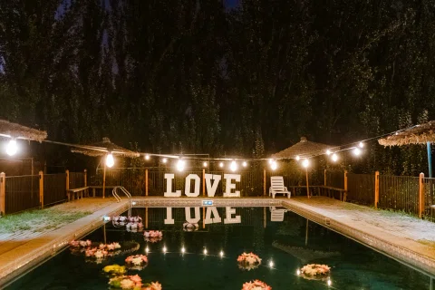 Letras LOVE iluminadas junto a la piscina durante la noche.