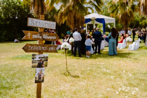 Letrero de madera con varias indicaciones instalado en el jardín de la ceremonia.