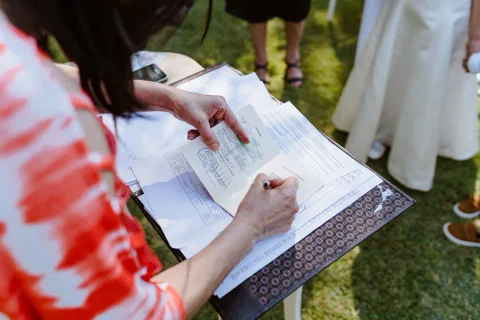 Primer plano de unas manos escribiendo en un documento apoyado sobre una carpeta.