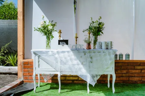 Mesa de ceremonia con mantel blanco y pequeñas plantas decorativas.