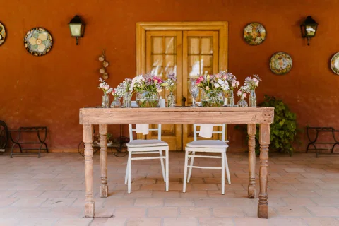 Mesa rústica decorada con flores preparada para la ceremonia exterior.