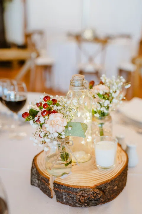 Mesa con velas, frascos, flores y una copa de vino.