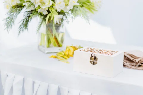 Mesa blanca con un florero, una caja decorativa y varios objetos pequeños.