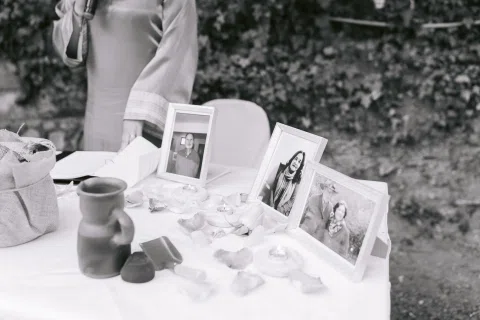 Mesa con tres fotografías enmarcadas, recipientes y pequeños objetos, en una fotografía en blanco y negro.